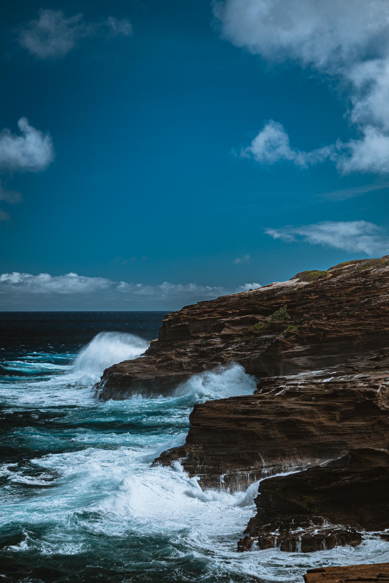 Wave at peak impact against lava cliff